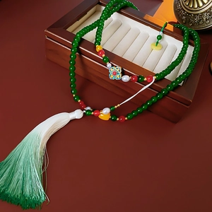 Detail of beaded floral necklace with green jade stones and elegant silk tassel