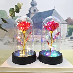 Detail of red gold foil artificial rose in glass dome with warm LED fairy lights glow