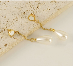 Detail of 18K gold stainless steel drop earrings with shell stud and teardrop pearls