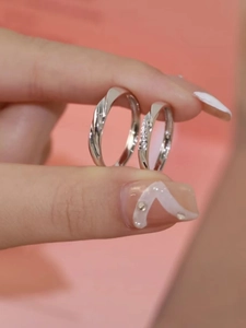 Macro detail of silver couple rings with twisted band and pave setting on pink background