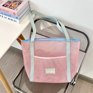 Close-up of pink mesh beach tote showing light blue straps and exterior pocket detail