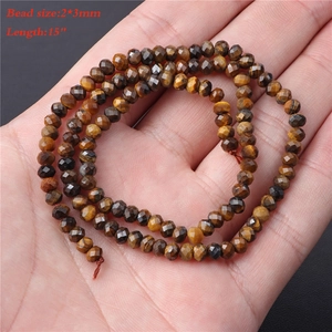 Macro detail of 2x3mm natural tiger eye faceted abacus beads held in hand for DIY jewelry