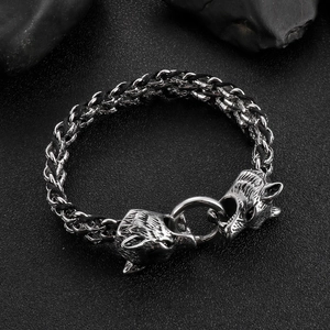 Close-up of dual wolf head clasps on braided black leather and steel chain bracelet