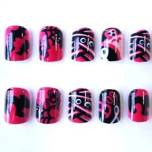 Pink Halloween press-on nails featuring spooky ghost, spider web and bat designs