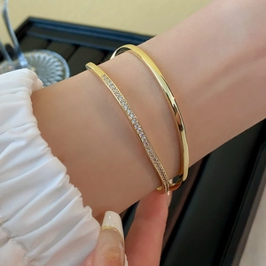 Close-up of gold-plated bangle set featuring a minimalist ring and a pavé zircon band