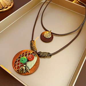 Détail d'un collier vintage avec pendentifs en bois et oiseau en bronze sur cordon