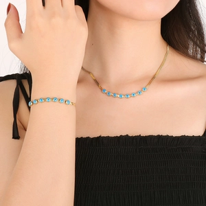 Golden snake chain necklace and bracelet set with blue evil eye charms on female model