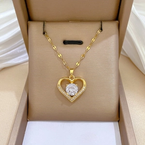 Macro shot of gold heart necklace with central crystal in beige gift box on white silk