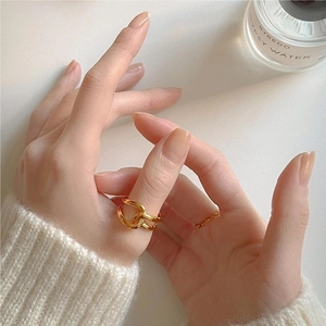 Close-up of a minimalist golden double twisted ring worn in a cozy lifestyle setting
