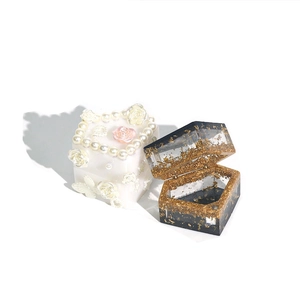 Detailed macro view of DIY resin jewelry boxes with floral accents and gold foil flakes