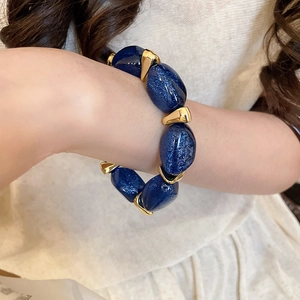 Close-up of starry blue acrylic oval beads and gold spacers on a beaded bracelet