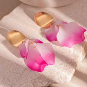 Detailed macro view of pink gradient acrylic petal earrings with golden textured studs