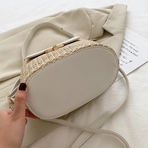 Detailed view of straw bucket bag with white leather base and golden metal buckle