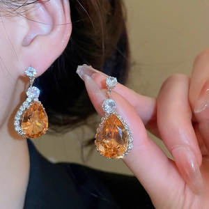 Detail of silver drop earrings with pear-cut orange gems and white zircon inlay