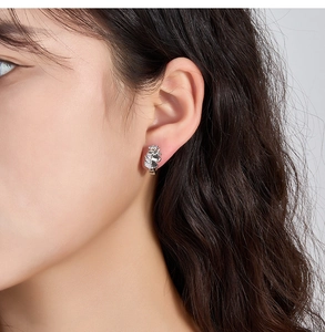 Detail view of a silver unicorn hoop earring with white cubic zirconia on a female model