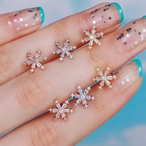 Snowflake zircon stud earrings in rose gold, silver, and gold finishes shown on fingers