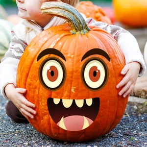 Close-up of a child holding a large orange pumpkin decorated with a cartoon smiley face sticker