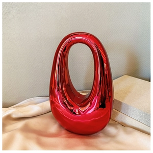 Close-up of a red metallic oval acrylic evening bag on soft silk fabric and gift box