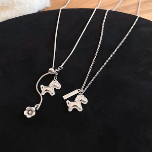 Macro detail of silver horse necklaces with zircon and Lucky tag on black velvet