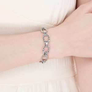 Close-up of silver chunky cable chain bracelet on model with textured fabric background