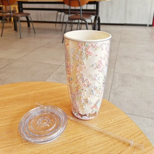 Top view of a double-layered plastic straw cup with colorful foam beads inside the lid