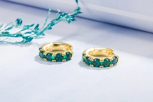 Macro shot of gold S925 sterling silver earrings featuring green round-cut zircon stones