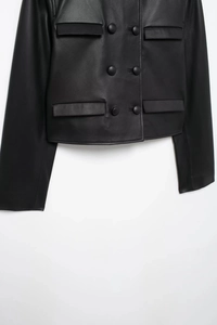 Close-up of black leather jacket waist and hem with double-breasted buttons and fine texture