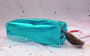 Teal laser pencil case with colorful tassel detail on a dreamy pink mesh background