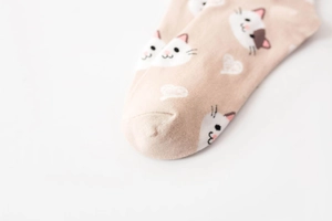 Close-up of cute cartoon cat pattern and heart prints on pink cotton socks for women