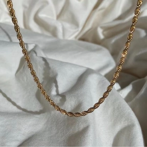 Golden titanium steel twist rope chain necklace on white satin fabric background