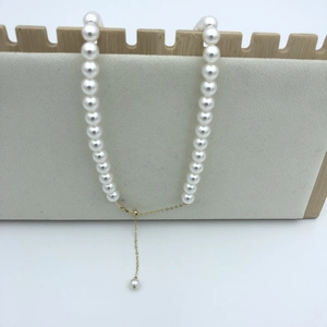 Detail of round white pearl necklace with 14k gold plated adjustable chain and pendant