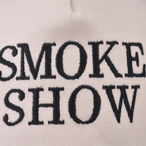 Gros plan de la broderie SMOKE SHOW sur une casquette de baseball en coton beige sergé