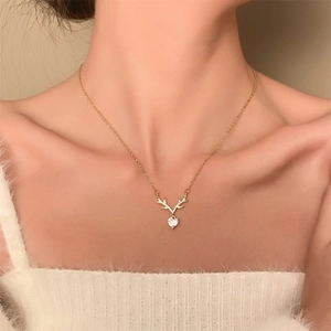 Detail view of heart-shaped crystal reindeer necklace with gold antlers on a female model