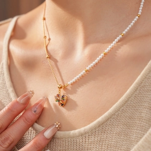 Detailed shot of an asymmetric pearl necklace featuring a colorful gemstone heart pendant