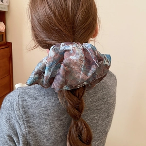 Detail view of large marble-patterned chiffon hair scrunchie on a stylish braided ponytail