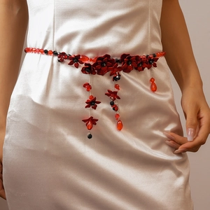 Detail of red flower beaded waist chain with black accents on a white satin dress