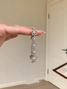 Detail of silver floral lace bracelet featuring hollow five-petal flowers and small crystals