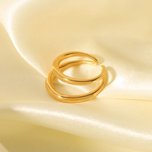 Detail eines 18K vergoldeten doppelten offenen Rings auf weichem beigem Satinstoff