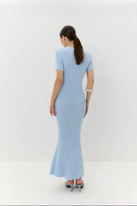 Dettaglio dell'abito in maglia azzurro che mostra la trama a coste e il taglio a sirena aderente