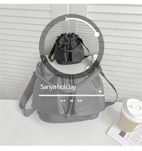 Detail of black nylon bucket bag featuring sturdy handles and adjustable wide shoulder strap