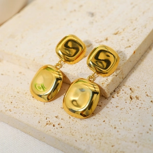 Detail showing gold irregular geometric square stud earrings on textured stone