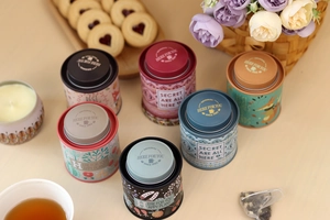 Various colored tin tea canisters arranged in a lifestyle tea set scenario