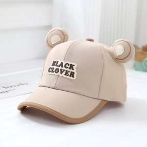 Détail de casquette enfant en coton beige avec oreilles d'ours 3D et broderie trèfle