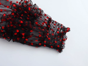 Detail of red heart flocked mesh fabric with elastic ruffled cuffs and lantern sleeves
