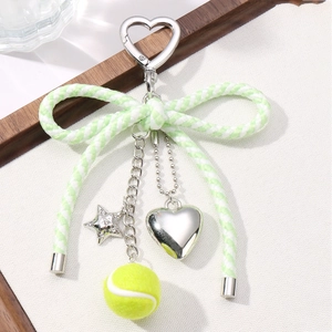 Light green bow keychain with heart star charms on a decorative wooden tray