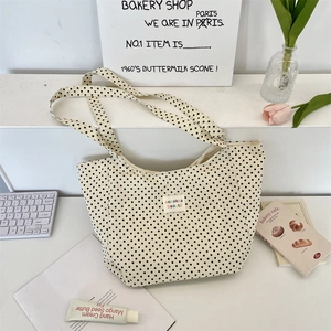 Detailed view of polka dot canvas tote bag with woven colorful label on office desk
