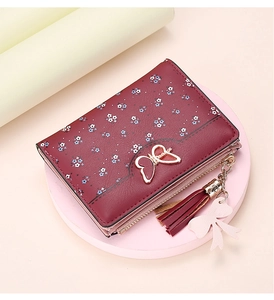 Macro detail of wine red floral wallet with golden butterfly clasp and leather tassel