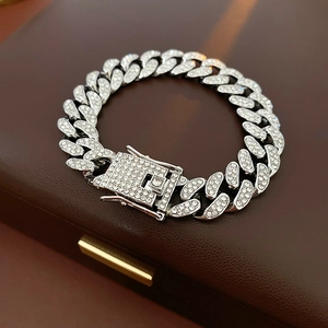Macro view of silver Cuban chain bracelet with sparkling rhinestones on leather background