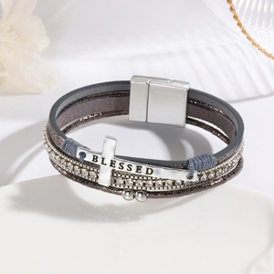Detailed close-up of multilayer leather bracelet with cross charm and magnetic clasp