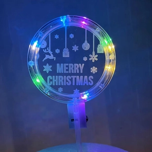 Macro shot of circular acrylic cake topper with festive LEDs and Merry Christmas engraving